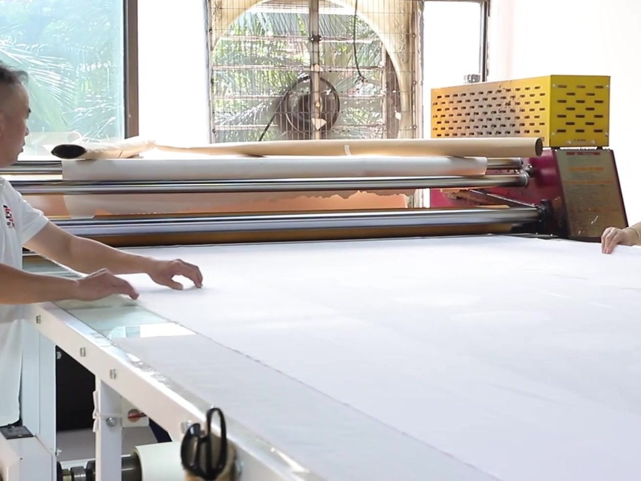 Heat press transferring an all-over fish print onto a custom fishing shirt panel