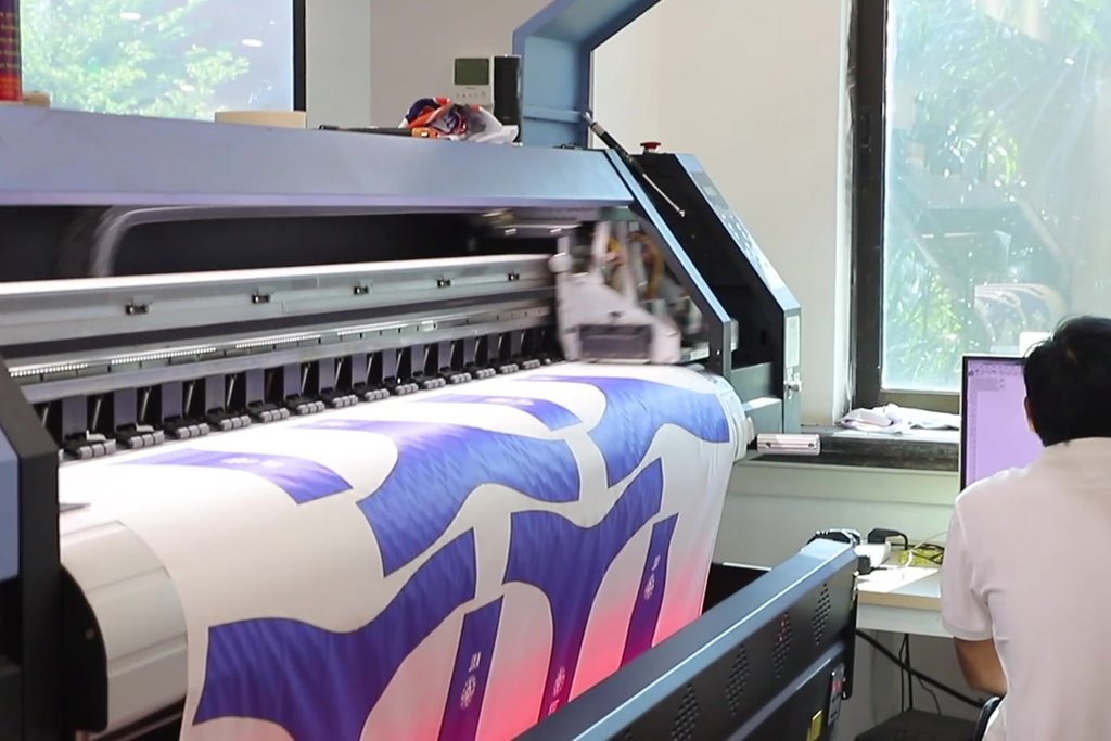 Large-format sublimation printer producing custom team jersey prints at Glory Ground factory