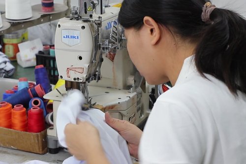 Sewing operator finishing a custom jersey at Glory Ground factory