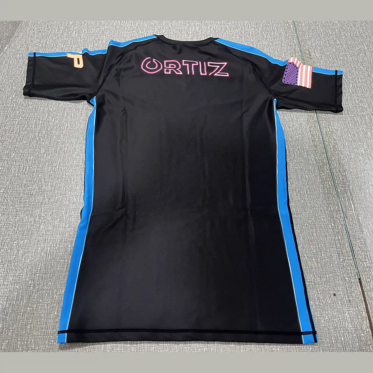 Custom short sleeve ranked rash guard in black with blue side panels, front and back
